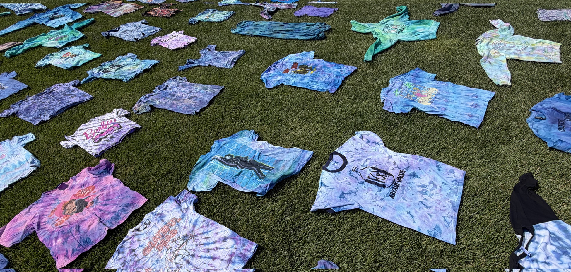 Tie-dyed shirts laid out on grass — The Dye Cult